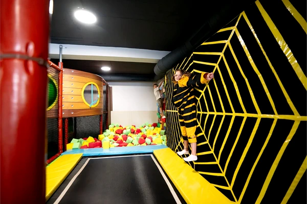 The black-and-yellow trampoline wall adds a distinctive physical challenge to the play center.